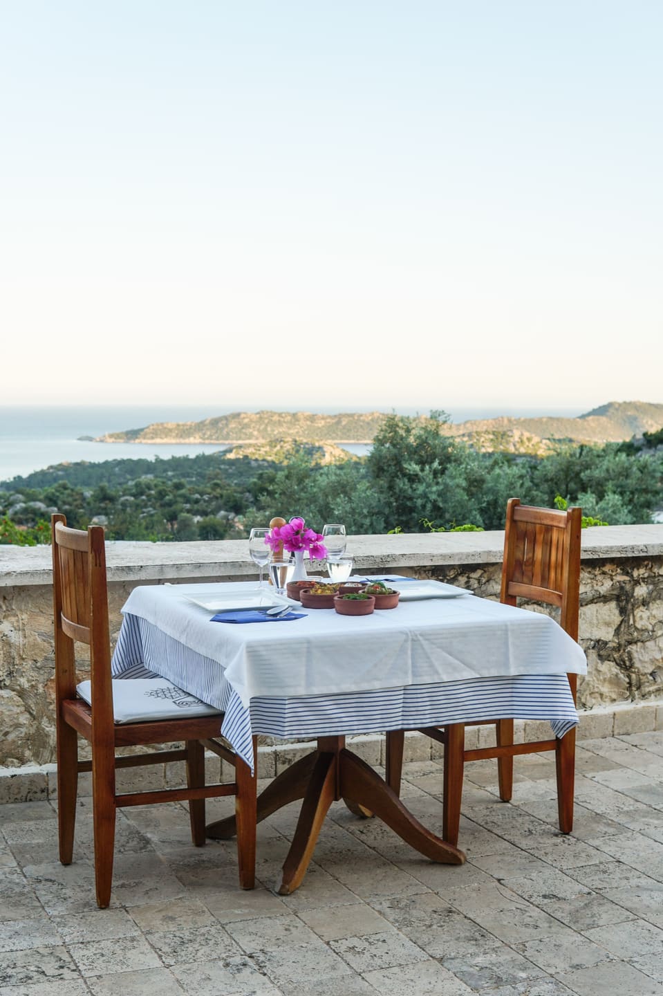 A dinner table set on the terrace with a sea view